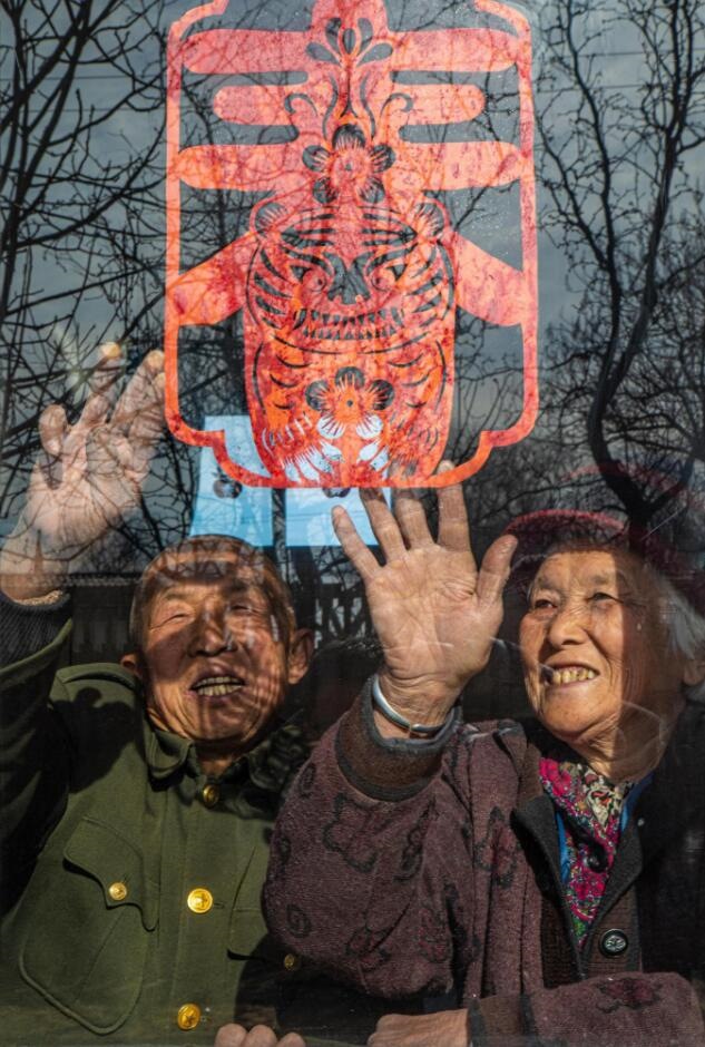 臘月里，霍州市師莊鄉(xiāng)馮南垣村村民師榮光(左)在災后重建的新家里貼窗花。(霍州市委宣傳部供圖)