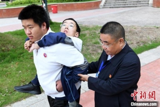 朱金祥背著鐘華強去教室上課的路上，也經(jīng)常碰到值班的校領(lǐng)導(dǎo)和老師前來搭把手。 卓忠偉 攝