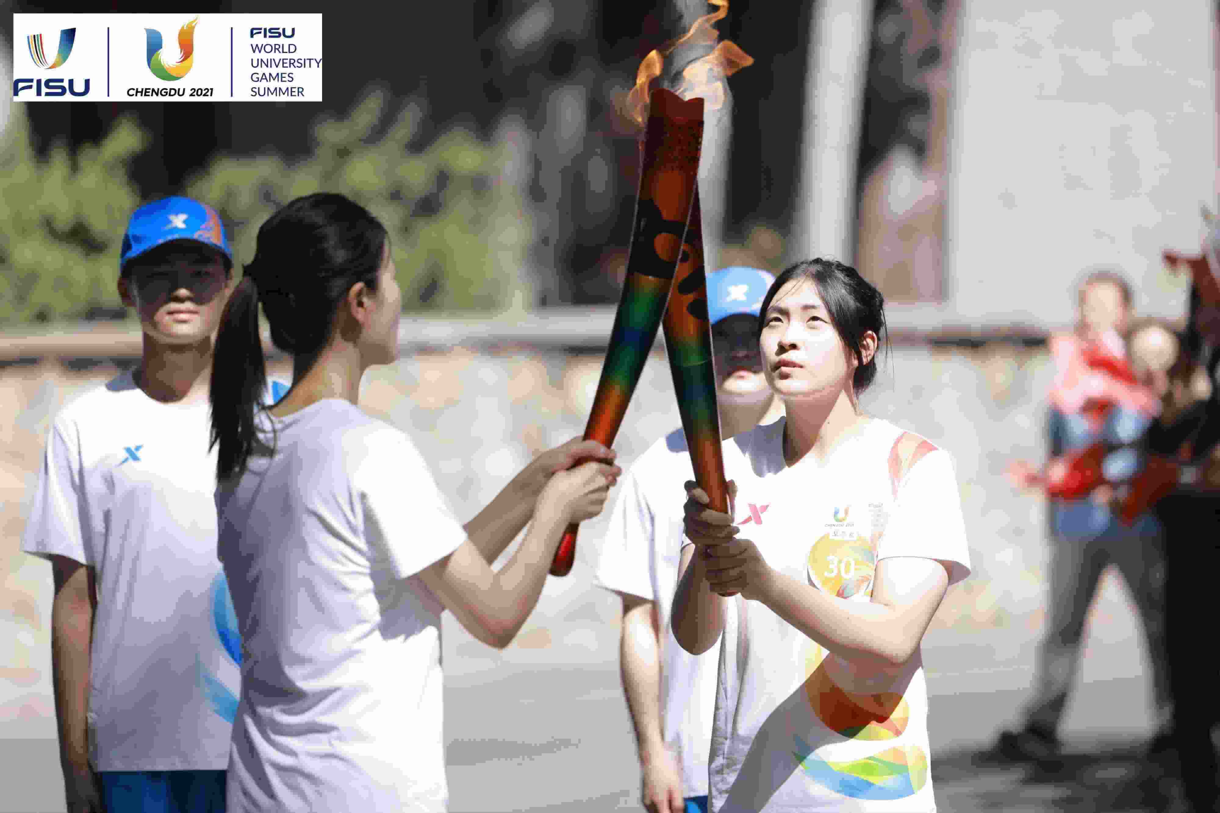 兩名大運(yùn)會(huì)火炬手進(jìn)行火炬?zhèn)鬟f。 圖片來源：成都大運(yùn)會(huì)執(zhí)委會(huì)供圖