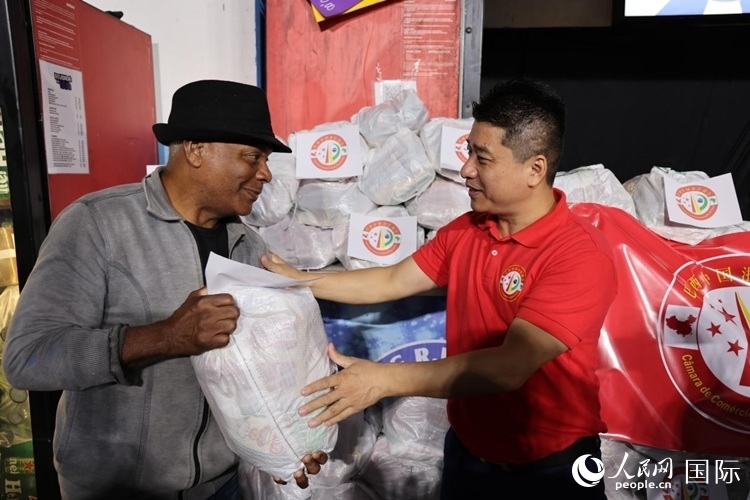 巴西中國浙江商會會長鄭俠茂向社區(qū)居民轉(zhuǎn)交捐贈物資。人民網(wǎng)記者 時元皓攝