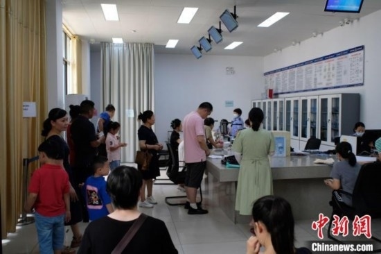 圖為在戶籍辦證廳內(nèi)排隊等待的家長和孩子。劉俊聰 攝