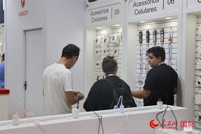 幾名參觀者在一個(gè)展臺前了解手機(jī)配件。（人民網(wǎng)記者 時(shí)元皓攝）