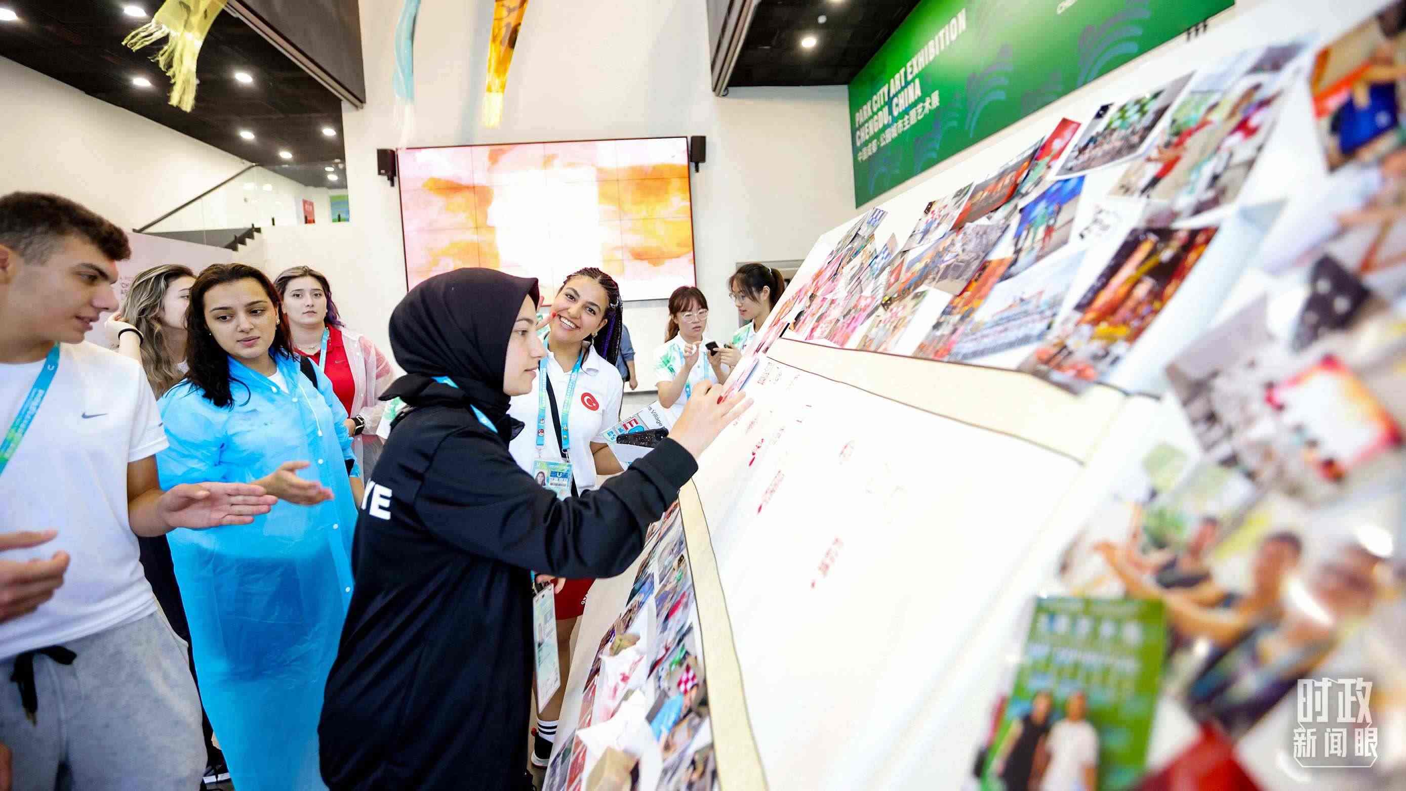 各國(guó)青年運(yùn)動(dòng)員正在參觀成都大運(yùn)村內(nèi)的“雪山下的公園城市，煙火里的幸福成都”主題藝術(shù)展。（總臺(tái)央視記者魏幫軍拍攝）