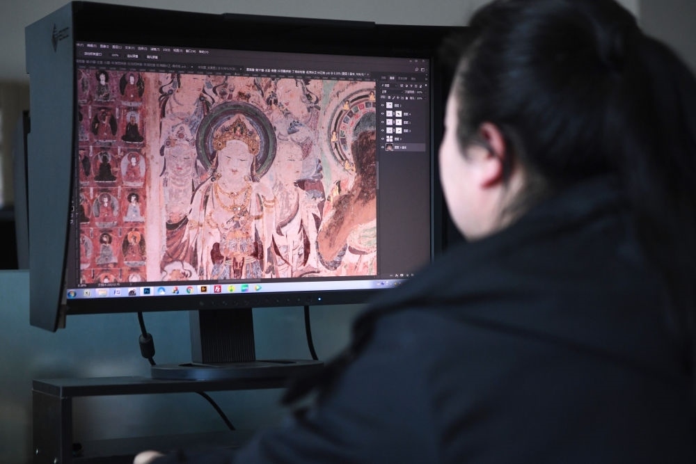敦煌研究院文物數(shù)字化保護(hù)團(tuán)隊(duì)圖像處理人員年海麗在拼接壁畫圖像（2023年4月25日攝）。數(shù)字化探索為莫高窟的保護(hù)與傳承開辟了全新路徑，數(shù)字技術(shù)讓敦煌文物走出洞窟，跨出國門，走向“永久保存、永續(xù)利用”。新華社記者 陳斌 攝