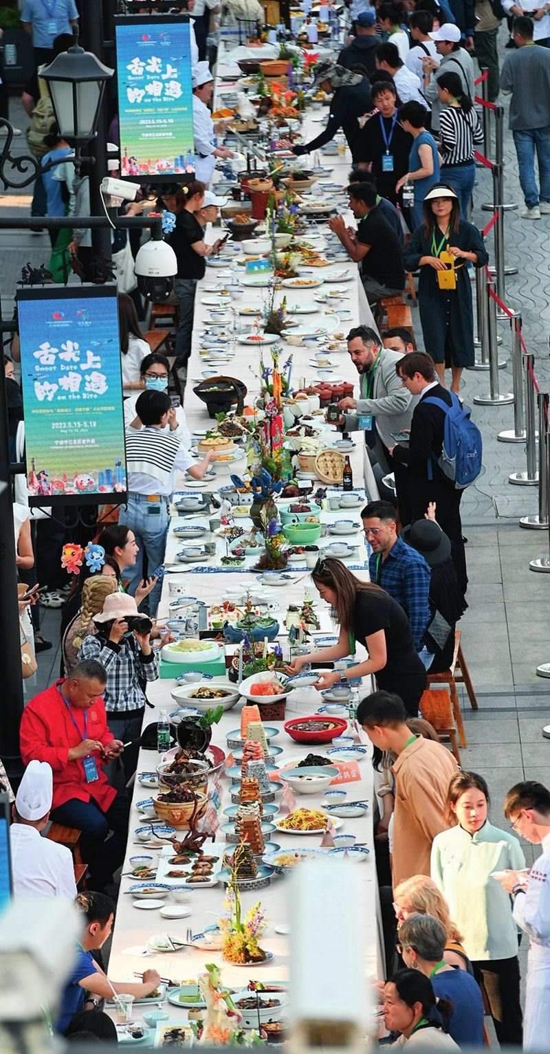 市民和游客在寧波舉辦的第三屆中國(guó)—中東歐國(guó)家博覽會(huì)暨國(guó)際消費(fèi)品博覽會(huì)上品嘗融合中國(guó)和中東歐美食的長(zhǎng)桌宴（2023年5月15日攝）。黃宗治攝/本刊