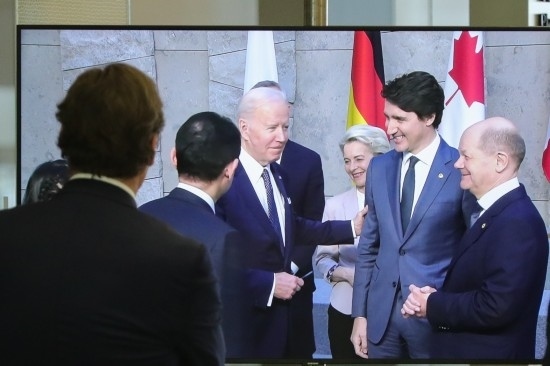 2022年3月24日，在比利時布魯塞爾的北約總部，一名男子觀看屏幕上美國總統(tǒng)拜登（右四）、歐盟委員會主席馮德萊恩（右三）、加拿大總理特魯多（右二）、德國總理朔爾茨（右一）出席七國集團(tuán)峰會合影儀式的畫面。新華社記者鄭煥松攝