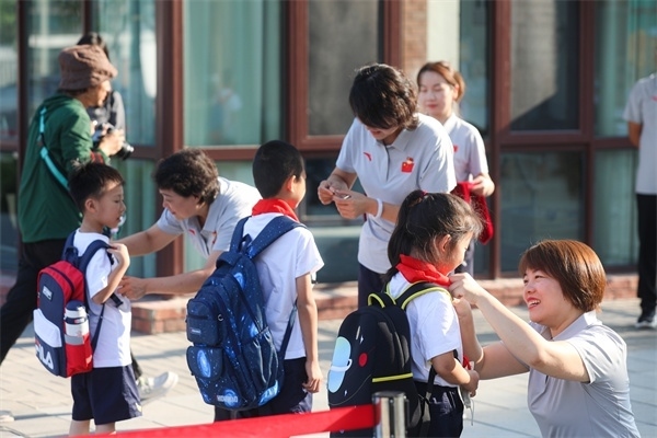 8月30日，雄安史家胡同小學學生體驗學校生活。老師為學生佩戴校徽。