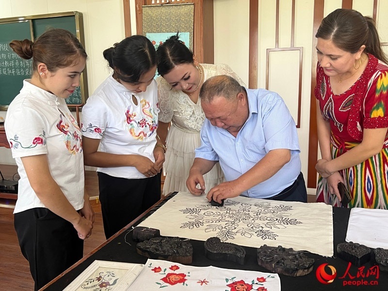 國家級非物質(zhì)文化遺產(chǎn)模戳印花布技藝傳承人吾吉阿西木?吾舒爾展示模戳印花布的制作過程。人民網(wǎng)記者 常雪梅攝