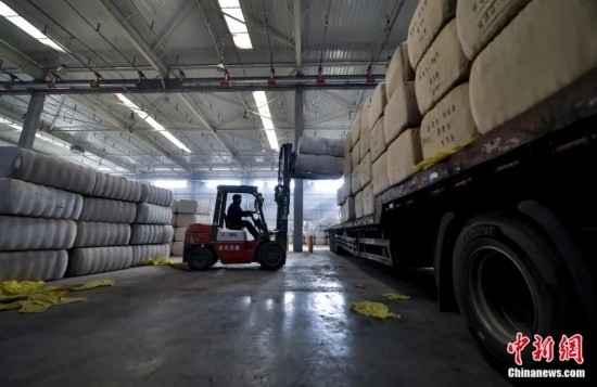 新疆喀什綜合保稅區(qū)，喀什啟路國際貿(mào)易有限公司的倉庫內(nèi)，工人正在裝載從塔吉克斯坦和烏茲別克斯坦進(jìn)口的棉花。劉新攝