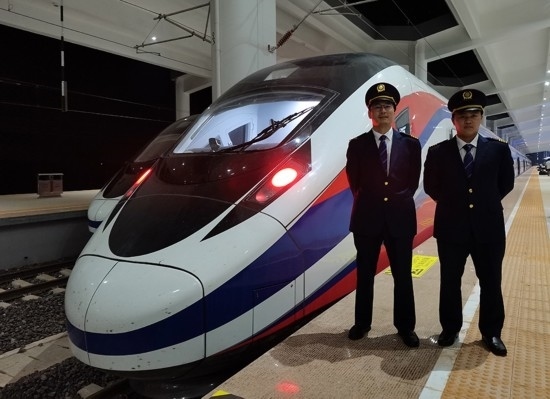 劉銀能（右一）與中國師父鄔俊鴻在動車組前合影。受訪者供圖