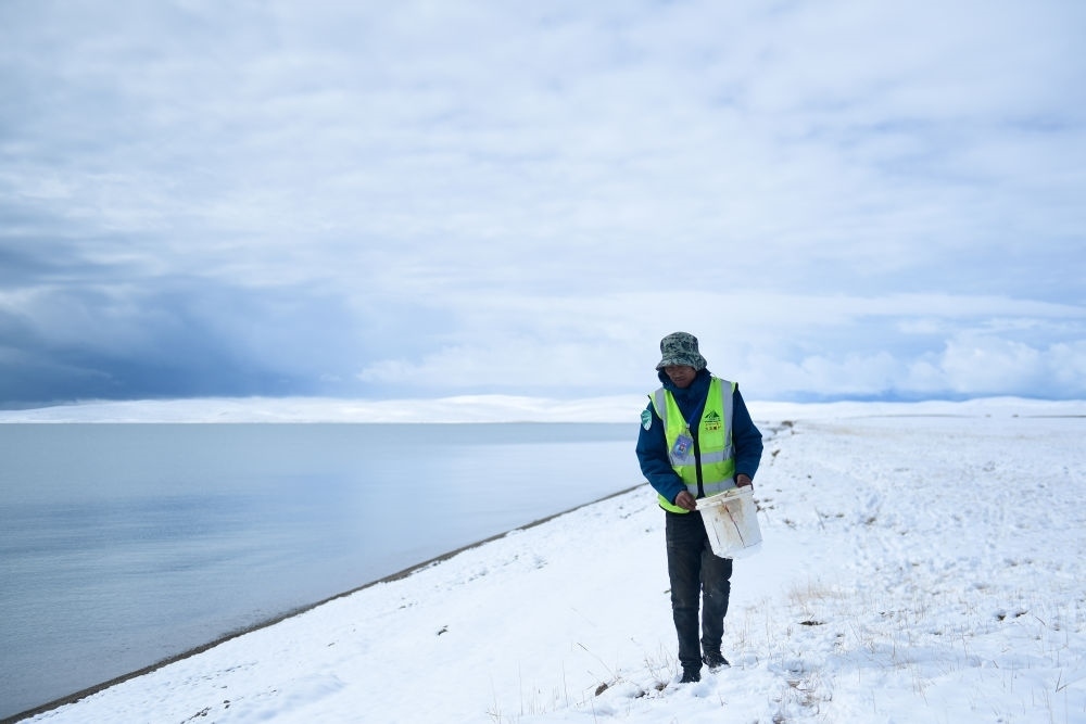 2021年10月20日，在青海省果洛藏族自治州瑪多縣扎陵湖鄉(xiāng)勒那村，三江源國(guó)家公園黃河源園區(qū)生態(tài)管護(hù)員在扎陵湖邊撿拾垃圾。新華社記者 張龍 攝
