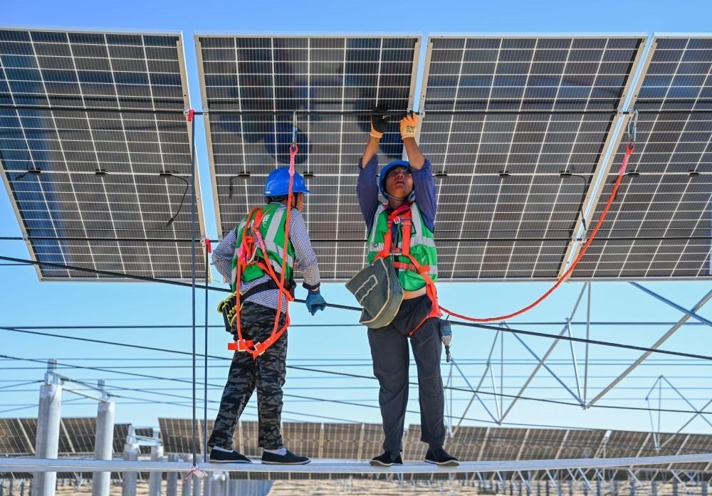 2023年7月22日，工人在位于內(nèi)蒙古杭錦旗庫(kù)布其沙漠億利生態(tài)示范區(qū)的蒙西基地庫(kù)布其200萬(wàn)千瓦光伏治沙項(xiàng)目工地安裝光伏板。新華社記者 劉磊 攝