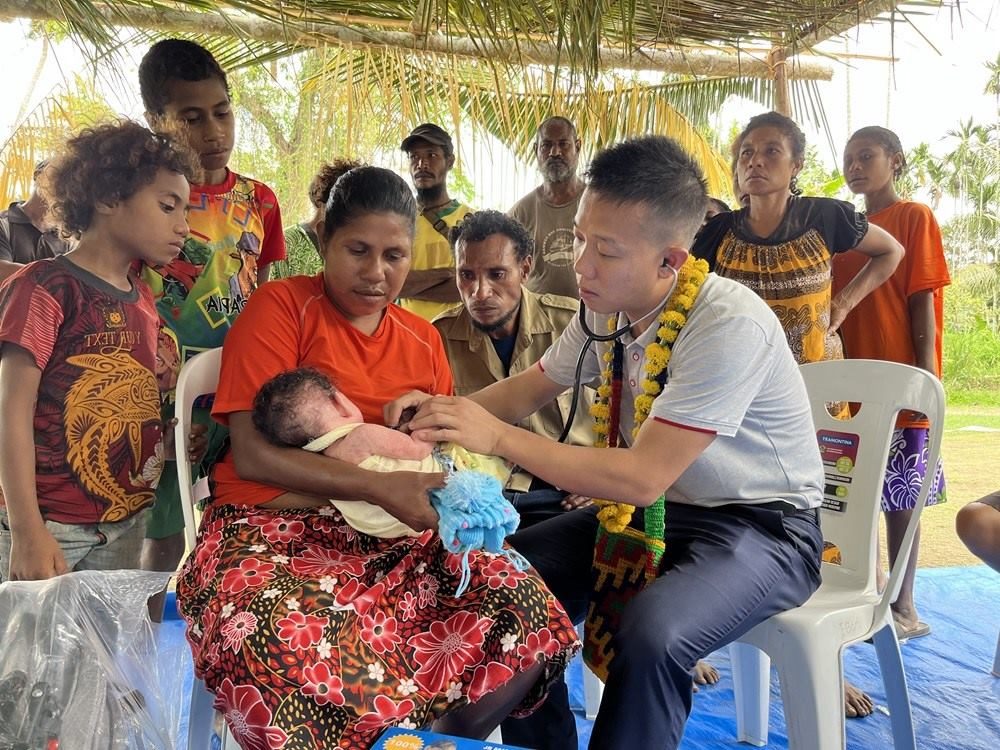 2023年8月5日，在巴布亞新幾內亞中央省的一個村莊里，第12批援巴新中國醫(yī)療隊副隊長、新生兒科副主任醫(yī)師劉振球為當?shù)貗雰郝犜\檢查。新華社發(fā)（第12批援巴新中國醫(yī)療隊供圖）