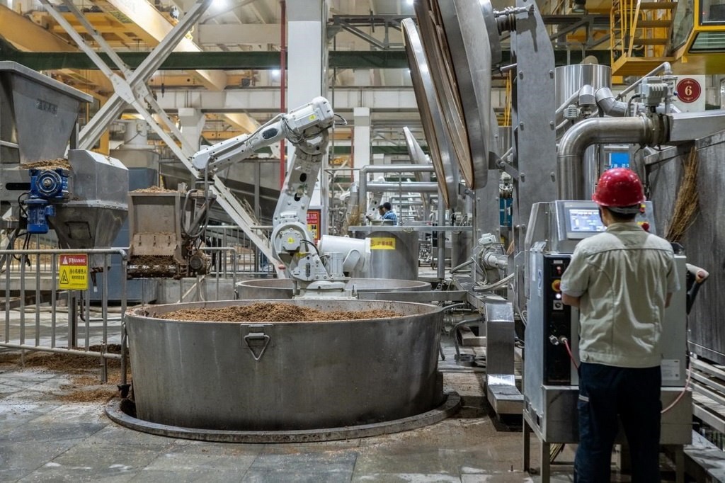 907車間里，機械臂正在撒料裝甑。嚴磊攝