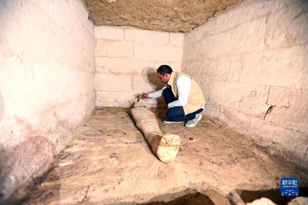 10月15日，在埃及明亞省考古現(xiàn)場(chǎng)，考古人員清理一座石鑿墓中的木乃伊。新華社發(fā)（艾哈邁德·戈馬攝）