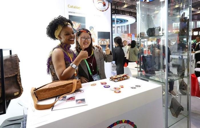 11月6日，一位參觀者（右）在第六屆進博會國家展南非展臺試戴傳統(tǒng)首飾。