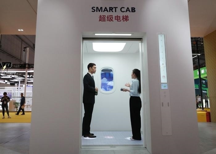 11月5日，工作人員（右）在第六屆進博會上向參觀者介紹奧的斯公司全新推出的超級電梯。