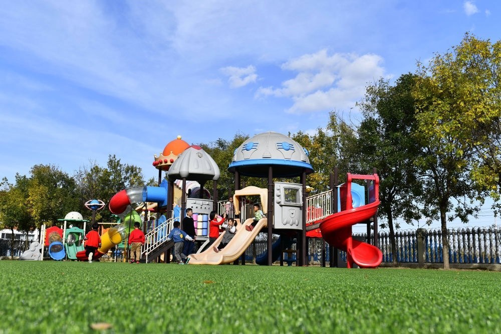 在山東省東營市墾利區(qū)楊廟社區(qū)幼兒園，孩子們在老師的帶領(lǐng)下進行戶外活動（2021年10月19日攝）。新華社記者 郭緒雷 攝