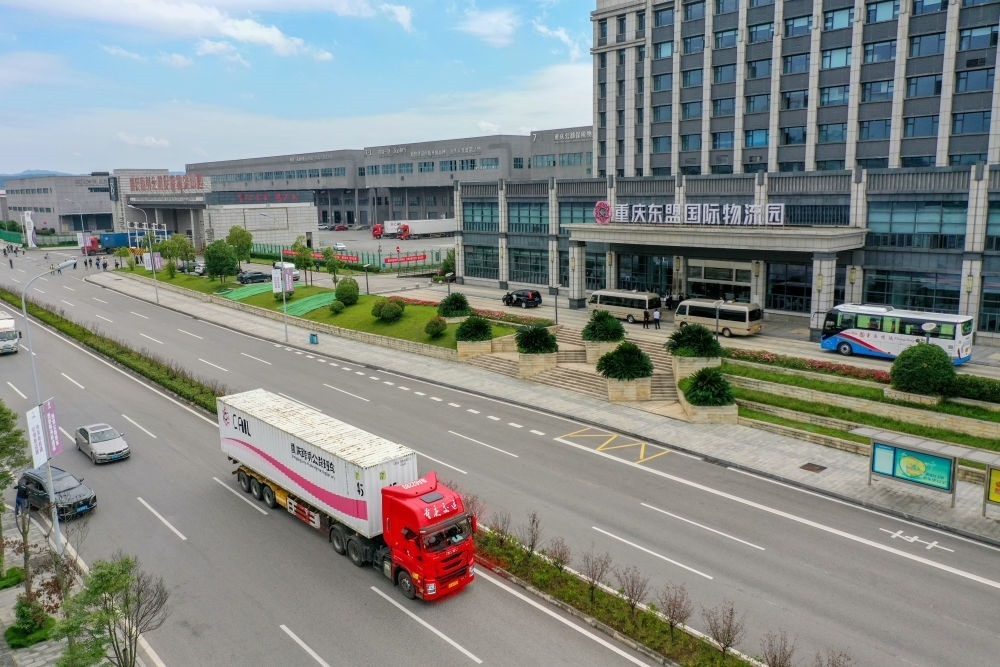 2023年10月11日，滿載筆記本電腦配件、發(fā)電機組件等產(chǎn)品的西部陸海新通道跨境公路班車從重慶南彭公路保稅物流中心駛出，將途經(jīng)廣西憑祥，直達越南（無人機照片）。新華社記者 黃偉 攝