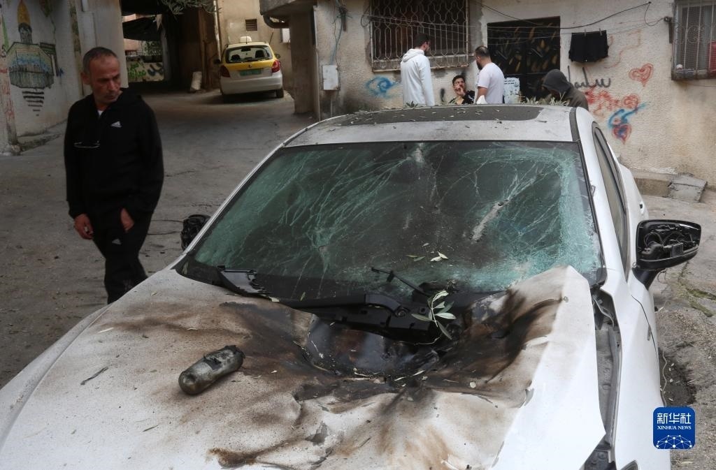 12月17日，在約旦河西岸城市圖勒凱爾姆附近的一處難民營，人們查看在沖突中損毀的車輛。新華社發(fā)（尼達(dá)爾·艾仕塔耶?dāng)z）
