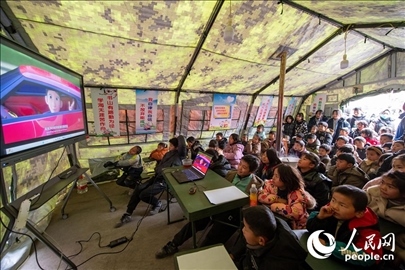 12月22日，在積石山縣大河家鎮(zhèn)大河村安置點(diǎn)，陸軍76集團(tuán)軍某旅搭建的“臨時(shí)學(xué)?！眱?nèi)，小朋友正在看動(dòng)畫片。人民網(wǎng)記者 翁奇羽攝