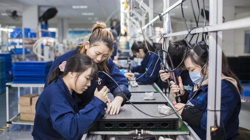 在新亞勝光電的產(chǎn)品線上，工人正進行產(chǎn)品組建和安裝布線。受訪者供圖