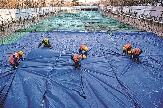 1月3日，房山區(qū)東風(fēng)街道，工人正在修復(fù)的河道內(nèi)給混凝土鋪設(shè)保溫布。