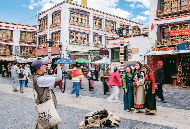 千年八廓街，見證民族團(tuán)結(jié)。2021年7月，習(xí)近平總書記來(lái)到位于西藏拉薩老城區(qū)的八廓街，感慨地說(shuō)：“千年八廓街，是我們各民族建起來(lái)的八廓街。各民族文化在這里交流交往交融，我們中華民族的大家庭在這里其樂(lè)融融?！眻D為2023年6月13日，游客身著藏裝在八廓街拍照留念。 新華社記者 姜帆/攝