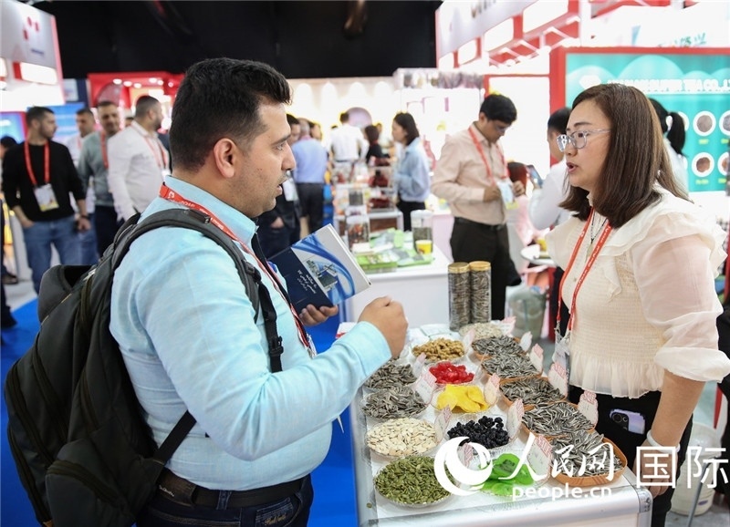 圖為一家中國(guó)干果參展企業(yè)代表與采購(gòu)商洽談。人民網(wǎng) 塔里克·易卜拉欣攝