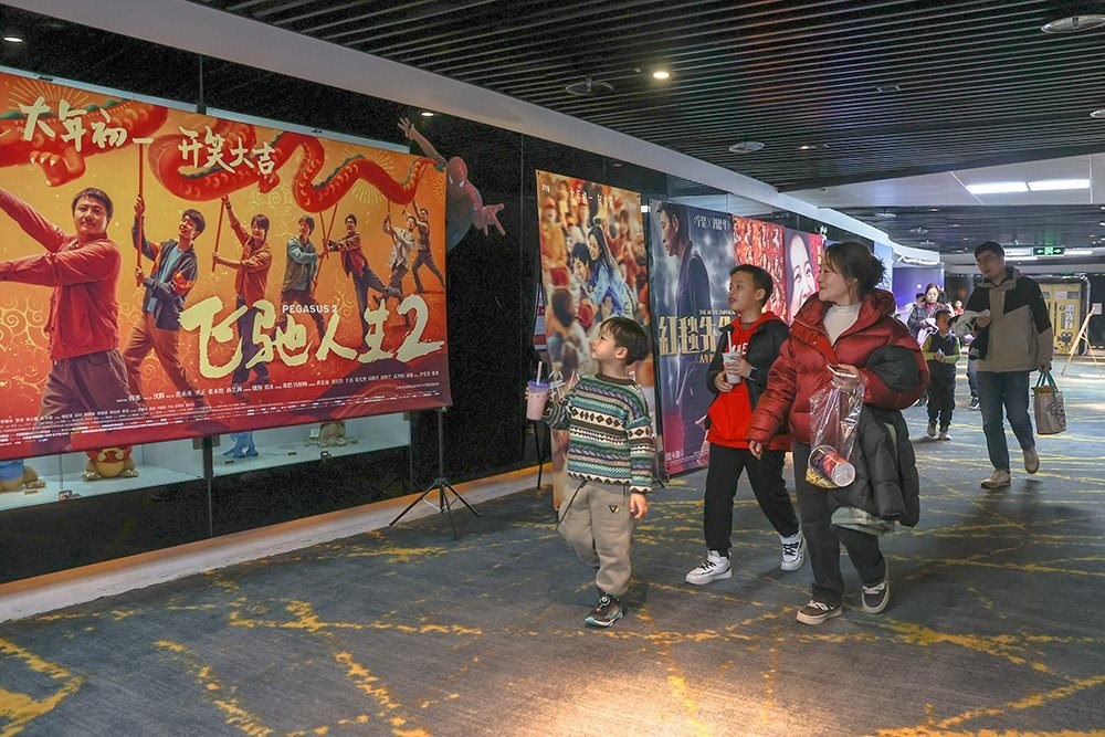 △ 2024年2月16日，在江西贛州一家電影院，觀眾從春節(jié)檔電影的宣傳展板前走過。