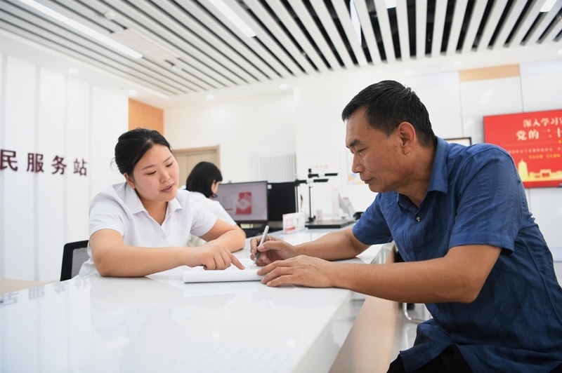 2023年5月23日，河北雄安新區(qū)容東片區(qū)南文營社區(qū)居民（右）在社區(qū)便民服務(wù)站辦理業(yè)務(wù)。