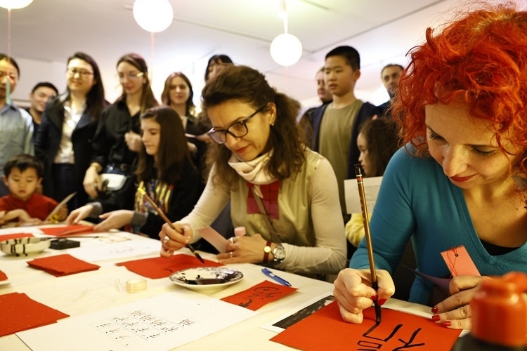 羅馬尼亞觀眾學(xué)習(xí)用毛筆寫(xiě)“?！弊帧Ｖ袊?guó)文化中心供圖
