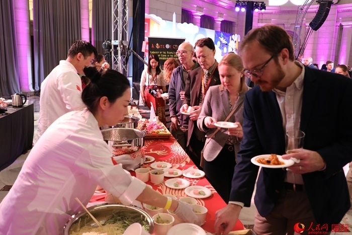 當(dāng)?shù)貢r間3月7日晚，華盛頓聯(lián)合車站廣場舉行駐美使團(tuán)“使館主廚挑戰(zhàn)賽”。圖為當(dāng)?shù)孛癖娫谥袊古_前體驗中國美食。人民網(wǎng)記者 李志偉攝