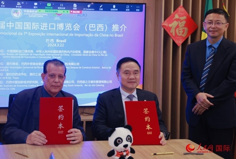 巴西外貿(mào)商會聯(lián)合會會長阿代爾·羅伯托（左）與中國國際進口博覽局副局長吳政平（中）現(xiàn)場簽訂協(xié)議。人民網(wǎng)記者 宋亦然攝