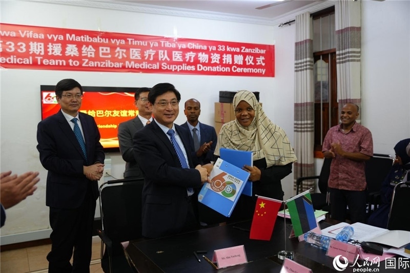 江蘇省蘇北人民醫(yī)院黨委書記束余聲與桑衛(wèi)生部首席秘書哈比巴交換捐贈(zèng)書。中國(guó)援桑醫(yī)療隊(duì)供圖