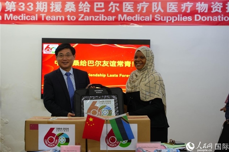 江蘇省蘇北人民醫(yī)院黨委書記束余聲捐贈(zèng)物資與桑衛(wèi)生部首席秘書哈比巴。中國(guó)援桑醫(yī)療隊(duì)供圖
