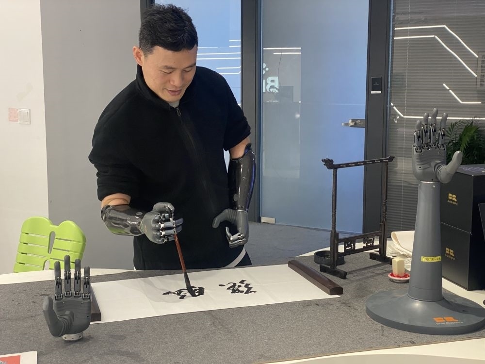 2024年3月29日，在浙江強(qiáng)腦科技有限公司展廳內(nèi)，失去雙手的產(chǎn)品體驗(yàn)官倪敏成依靠智能仿生手寫(xiě)毛筆字。新華社記者 魏一駿 攝