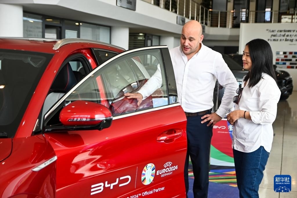2024年5月29日，在馬耳他比爾基卡拉，馬耳他哈桑-扎米特汽車公司首席執(zhí)行官德古阿拉（左）介紹一輛比亞迪純電動(dòng)汽車。新華社發(fā)（喬納森·博格 攝）