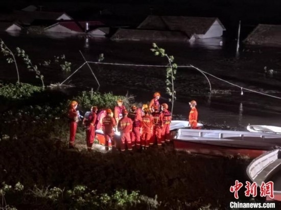  7月6日凌晨3時(shí)，在湖南岳陽華容縣團(tuán)洲垸洞庭湖一線堤防，救援人員剛剛完成一次救援任務(wù)，遠(yuǎn)處是被淹的民房。中新社記者 白祖偕 攝