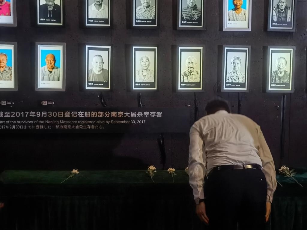 7月18日，人們向離世的南京大屠殺幸存者獻(xiàn)花、鞠躬。新華社記者邱冰清 攝