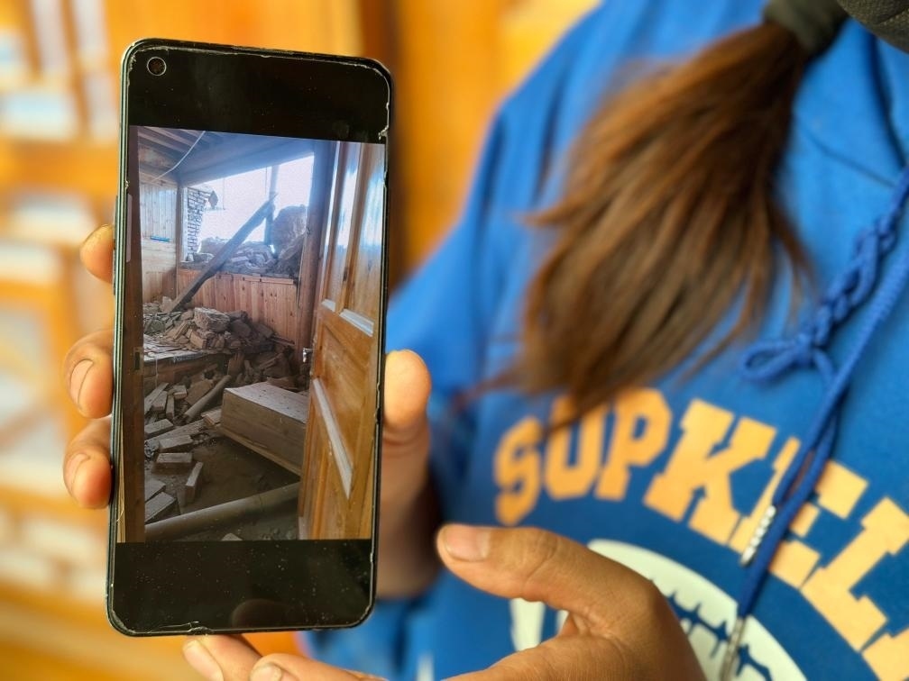 圖為7月17日拉毛東智在手機(jī)上找出地震后房屋受損的照片。新華社記者 張子琪 攝