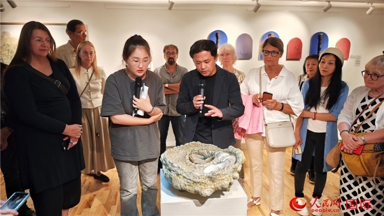 參展人、景德鎮(zhèn)陶瓷大學(xué)設(shè)計(jì)藝術(shù)學(xué)院副院長余劍峰（中）向來賓介紹參展作品。人民網(wǎng)記者 殷淼攝