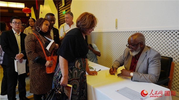 譚哲理在活動現(xiàn)場簽名贈書。人民網(wǎng) 劉暢攝