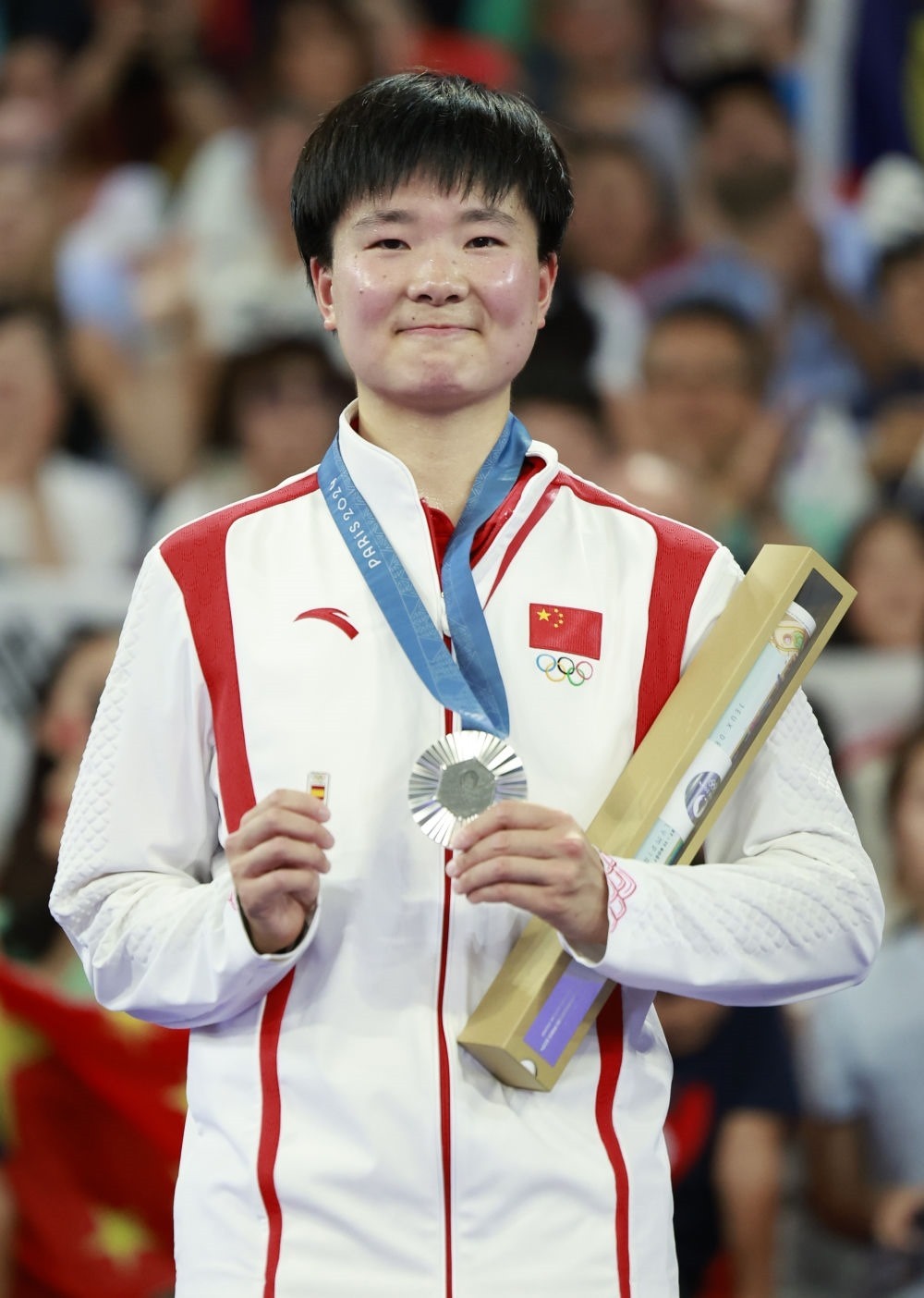 巴黎奧運會羽毛球女子單打亞軍、中國選手何冰嬌在頒獎儀式上一手握著銀牌，一手握著西班牙奧委會徽章（2024年8月5日攝）。新華社記者 任正來 攝