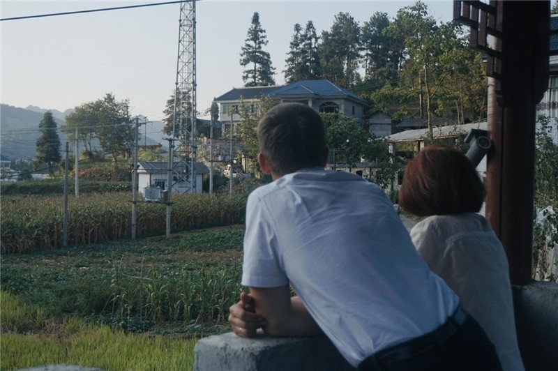 望得見山，看得見水，記得住鄉(xiāng)愁。每個(gè)人心中都有一個(gè)屬于自己的“花茂村”，在這方心田，走遍千山萬水，鄉(xiāng)音未改鬢毛衰。吉爾吉斯斯坦《比什凱克晚報(bào)》第一副總編輯妮娜·尼奇博洛娃與《中國與俄羅斯》雜志社社長奧列格·別列日內(nèi)赫攝在花茂村民居屋檐下并肩佇立，眺望山水，尋覓鄉(xiāng)愁。（李光裕攝）