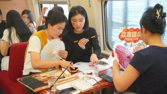 10月1日，旅客們?cè)贕1634次列車上給油紙傘作畫(huà)。新華社記者周義 攝
