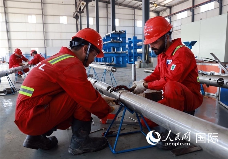 中伊員工共同在檢修鉆井設(shè)備。人民網(wǎng)記者管克江攝