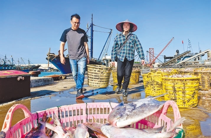 許小斌（左）和漁民一起搬運海鮮。本報記者 付 文攝