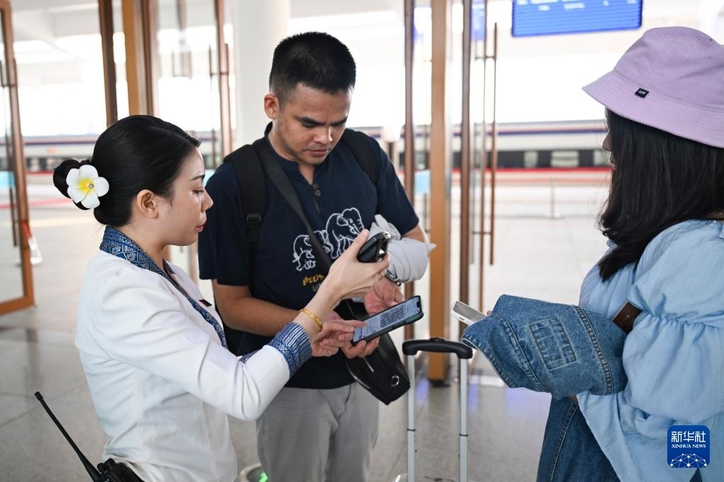 10月12日，在老撾萬象中老鐵路萬象站，工作人員檢驗(yàn)乘客車票。新華社記者 程一恒 攝