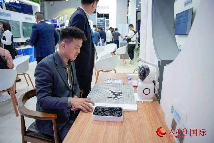 觀眾在中國移動國際有限公司展臺體驗智慧圍棋機器人。人民網(wǎng) 塔里克·易卜拉欣攝